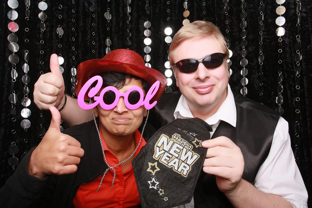 a happy couple sitting in a black tie photobooth